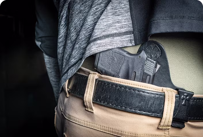 A firearm securely holstered and concealed within a waistband.